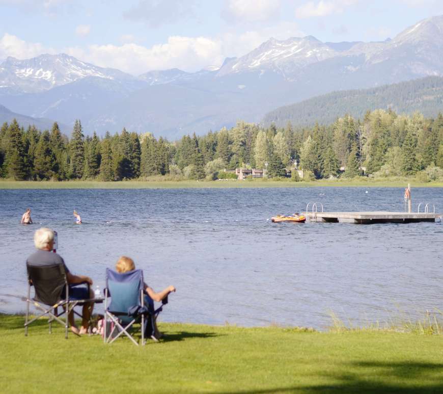 two people sitting in chairs looking at a lake